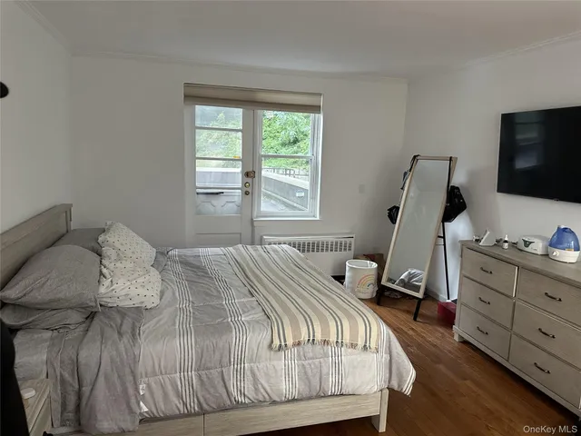 a bedroom with a bed and flat tv screen on the dresser