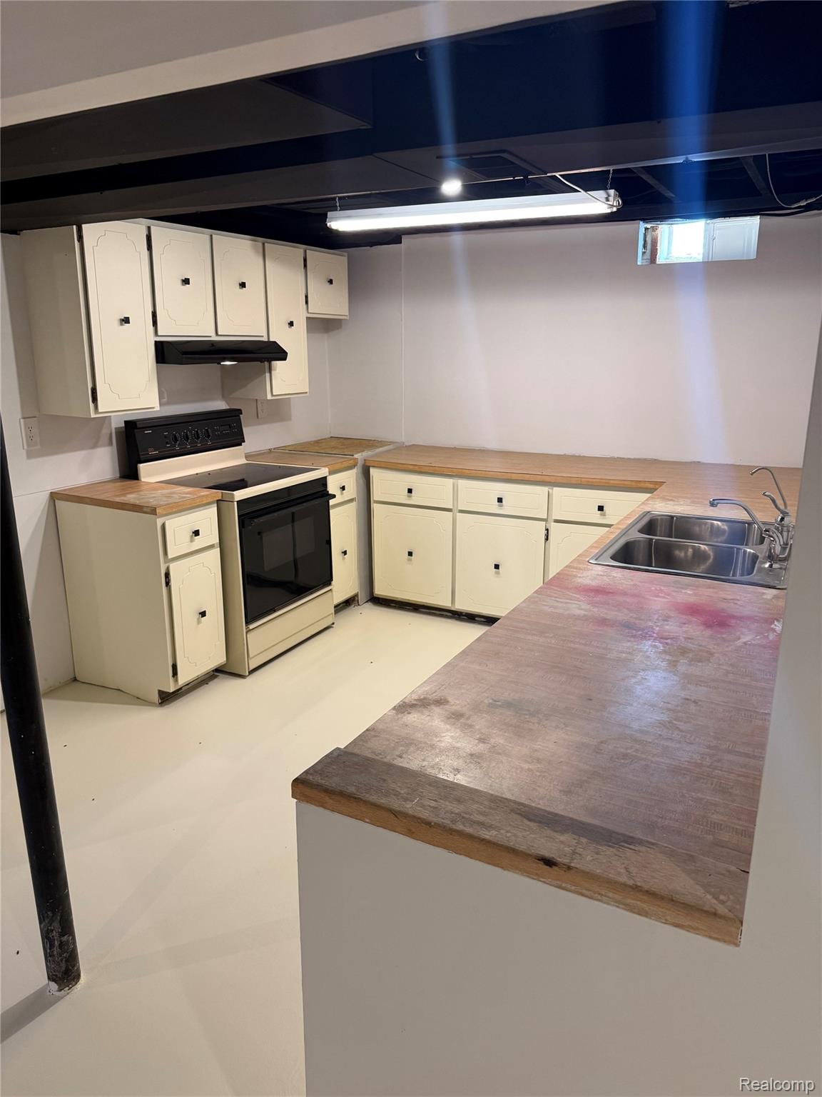 11779 Dunn Road Memphis, MI 48041 - Photo 39 of 44 Cream cabinetry with black hardware, wood-finish countertops, stainless steel double basin sink, and a black range with an overhead exhaust fan