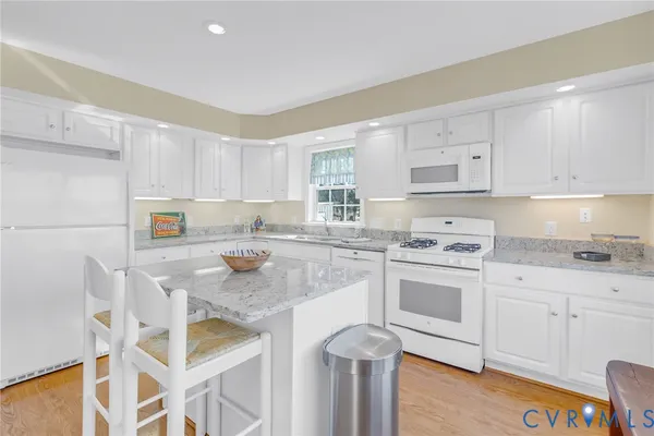 a kitchen with granite countertop white cabinets and white appliances