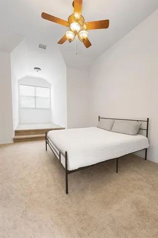 a bedroom with a bed and a chandelier fan