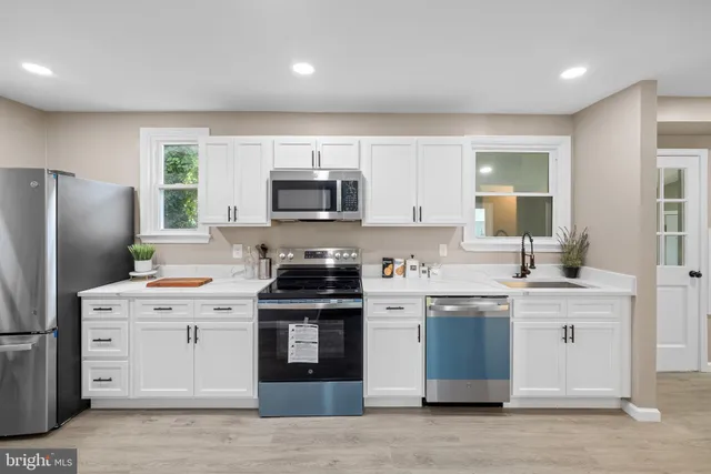 a kitchen with a sink a stove a refrigerator cabinets and a window