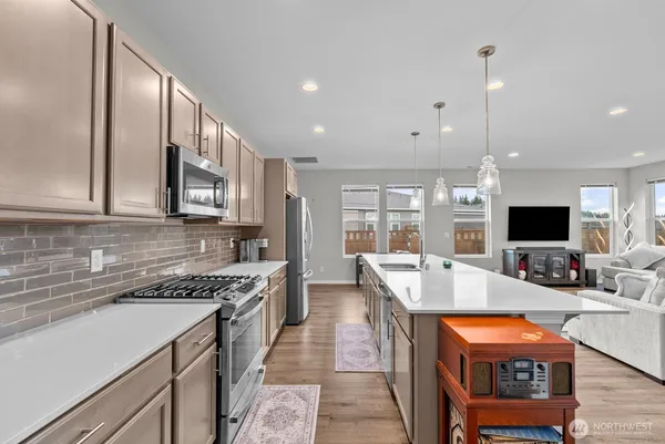 a large kitchen with stainless steel appliances granite countertop a stove and a view of living room