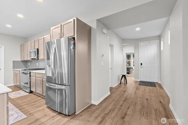 a kitchen with kitchen island wooden floors appliances and cabinets
