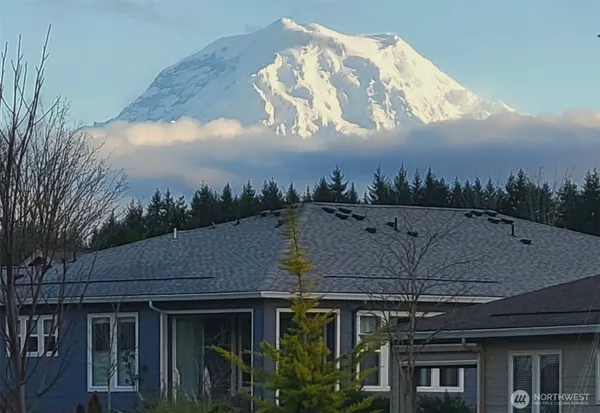 a front view of a house with a yard and mountain view in back