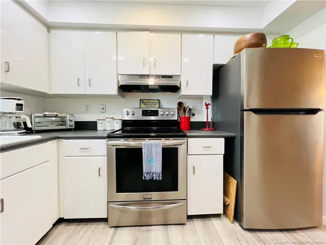 a kitchen with a refrigerator and a stove top open