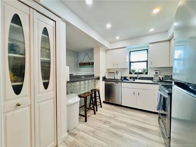 a kitchen with granite countertop a stove a sink and a refrigerator