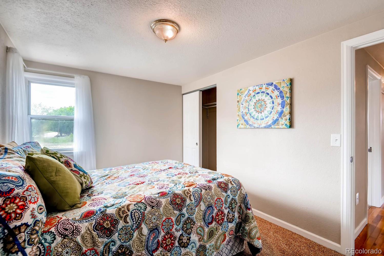1760 South Java Way Denver, CO 80219 - Photo 13 of 28 a bedroom with a bed and painting on the wall