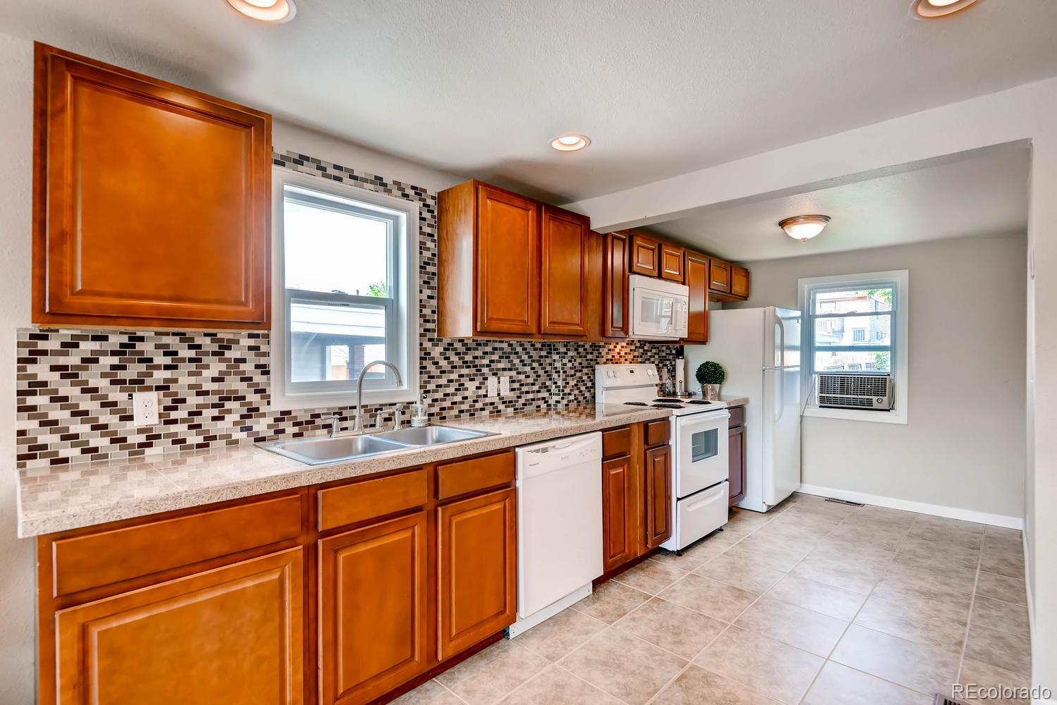 1760 South Java Way Denver, CO 80219 - Photo 9 of 28 a kitchen with stainless steel appliances granite countertop a stove a sink and a microwave
