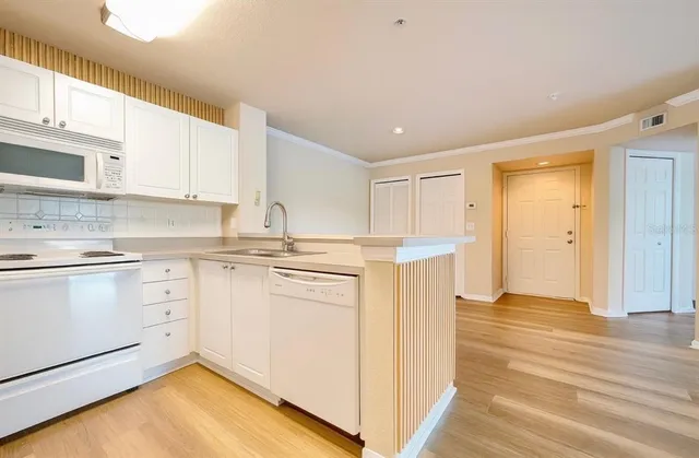 a kitchen with granite countertop white cabinets and white appliances