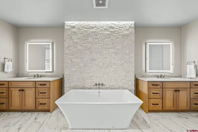 a spacious bathroom with a tub sink and mirror