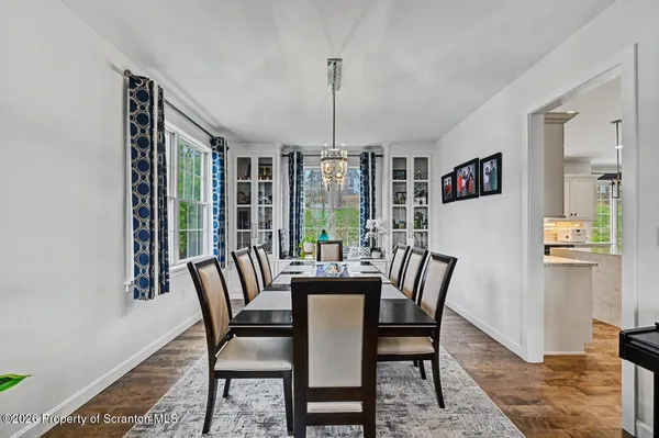 a view of a dining room with furniture a chandelier and large windows