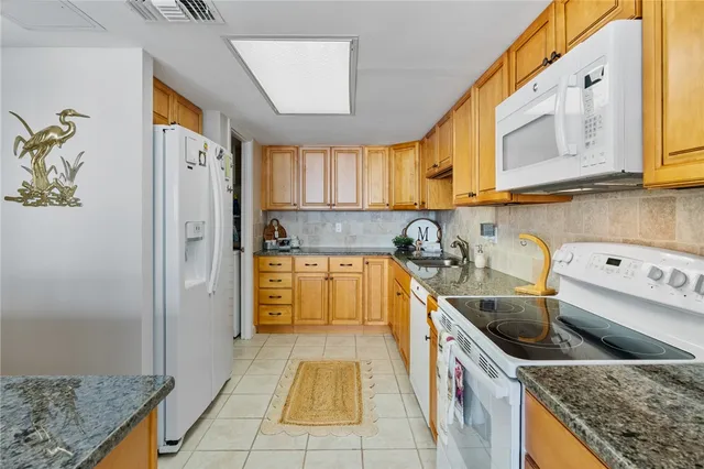 a kitchen with stainless steel appliances granite countertop a sink a stove and a refrigerator
