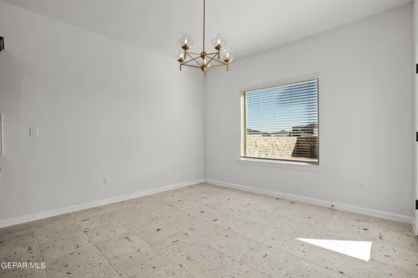an empty room with a chandelier fan and windows