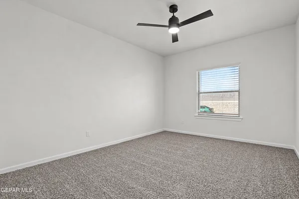 an empty room with a window and a ceiling fan