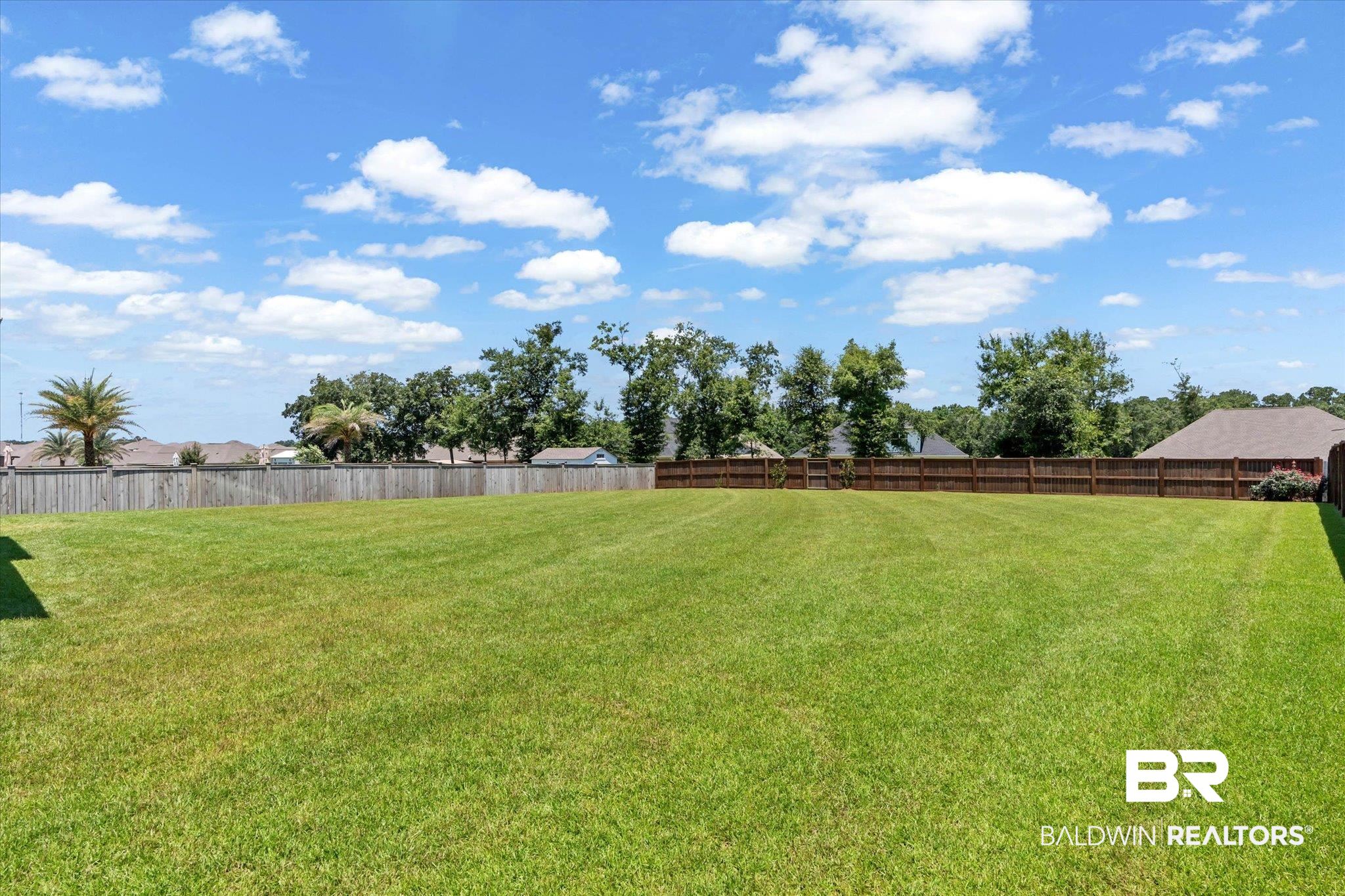 23523 Travis Stock Street Foley, AL 36535 - Photo 31 of 45 Spacious backyard featuring an expansive lawn, a full wood privacy fence, and mature trees in the surrounding landscape