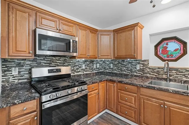 a kitchen with stainless steel appliances granite countertop a stove a sink and a microwave