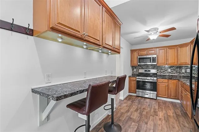 a kitchen with stainless steel appliances granite countertop a stove top oven a sink dishwasher and a microwave oven on the blue kitchen countertops