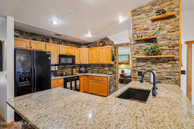 a kitchen with stainless steel appliances granite countertop a sink stove and refrigerator