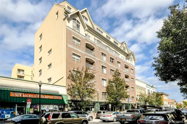 a front view of a building with parking lot of cars parked