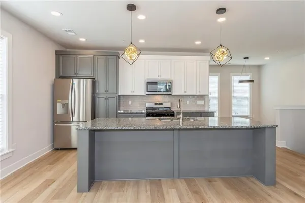 a kitchen with kitchen island granite countertop a sink a center island and stainless steel appliances