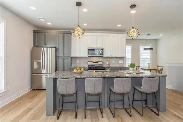 a kitchen with stainless steel appliances a dining table chairs refrigerator and microwave