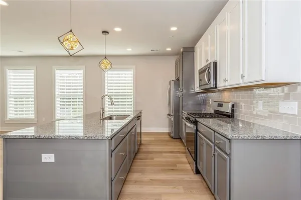 a kitchen with granite countertop stainless steel appliances a stove a sink a counter top space and cabinets