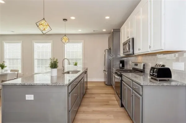 a kitchen with stainless steel appliances granite countertop a stove a sink and a granite counter tops with white cabinets