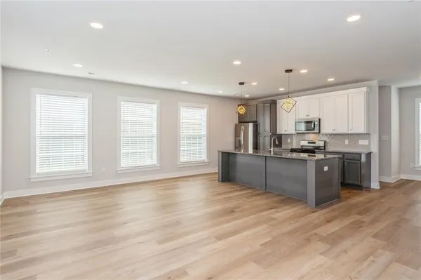 a large kitchen with stainless steel appliances granite countertop a large counter top and a wooden floors