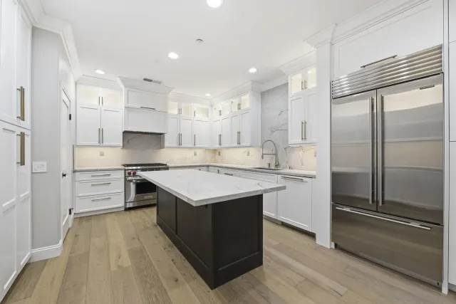 a large kitchen with stainless steel appliances kitchen island granite countertop a refrigerator and a stove top oven