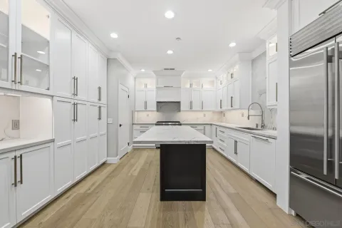 a large kitchen with stainless steel appliances kitchen island granite countertop a refrigerator and a sink