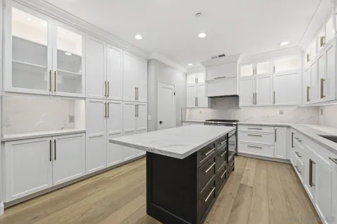 a kitchen with kitchen island white cabinets and wooden floor