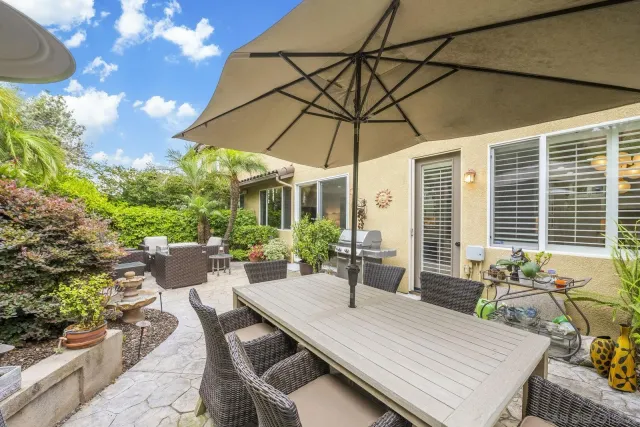 a view of an outside dining space with a table and chairs under an umbrella
