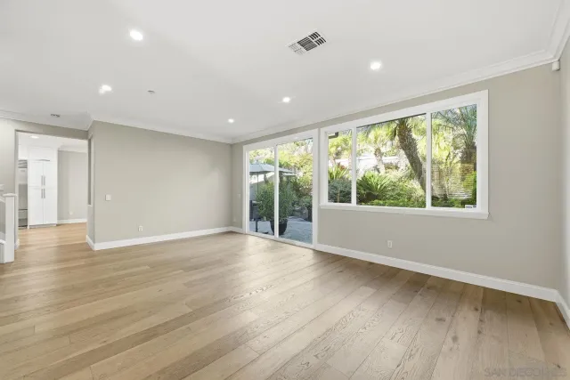 a view of an empty room with wooden floor and windows