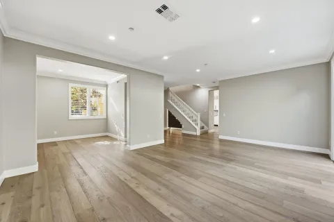 an empty room with wooden floor cabinet and windows