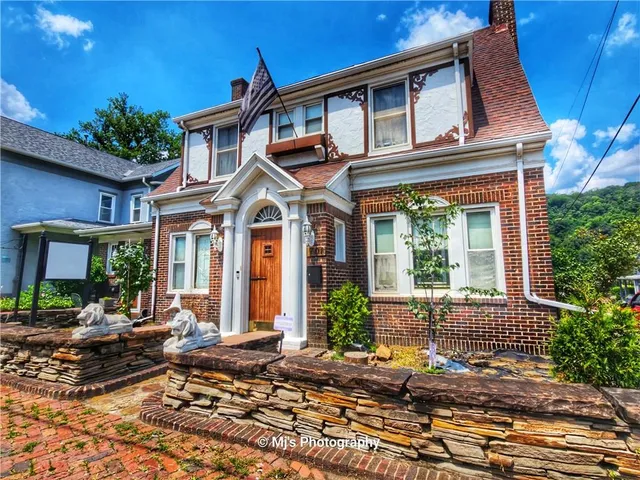 a view of a brick house with plants and large tree