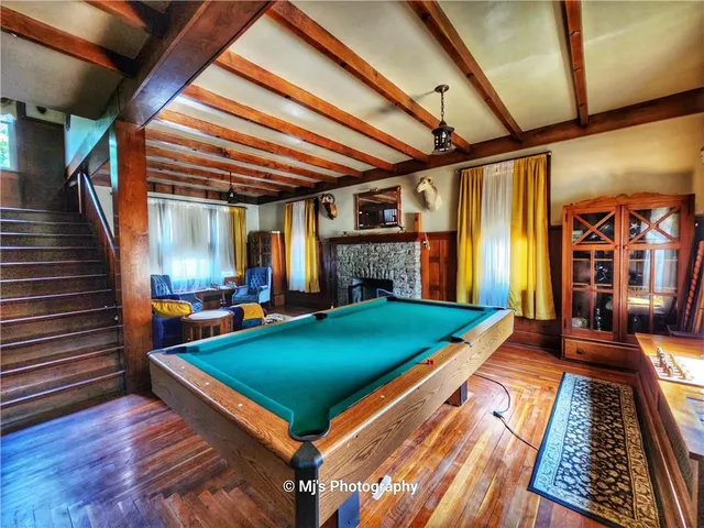 a room with pool table and wooden floor