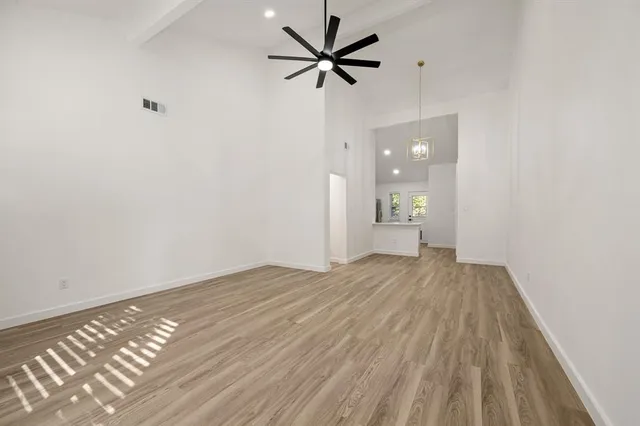 a view of empty room with wooden floor and a ceiling fan