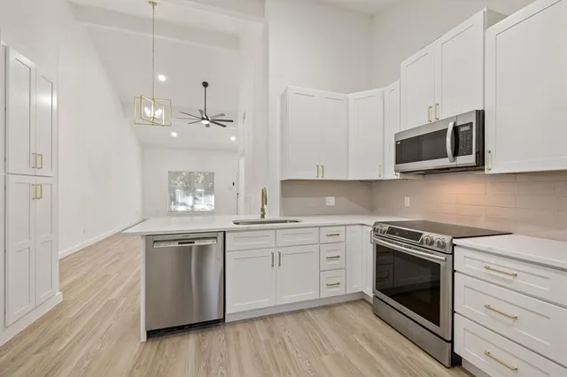 a kitchen with stainless steel appliances granite countertop a stove top oven a sink and white cabinets