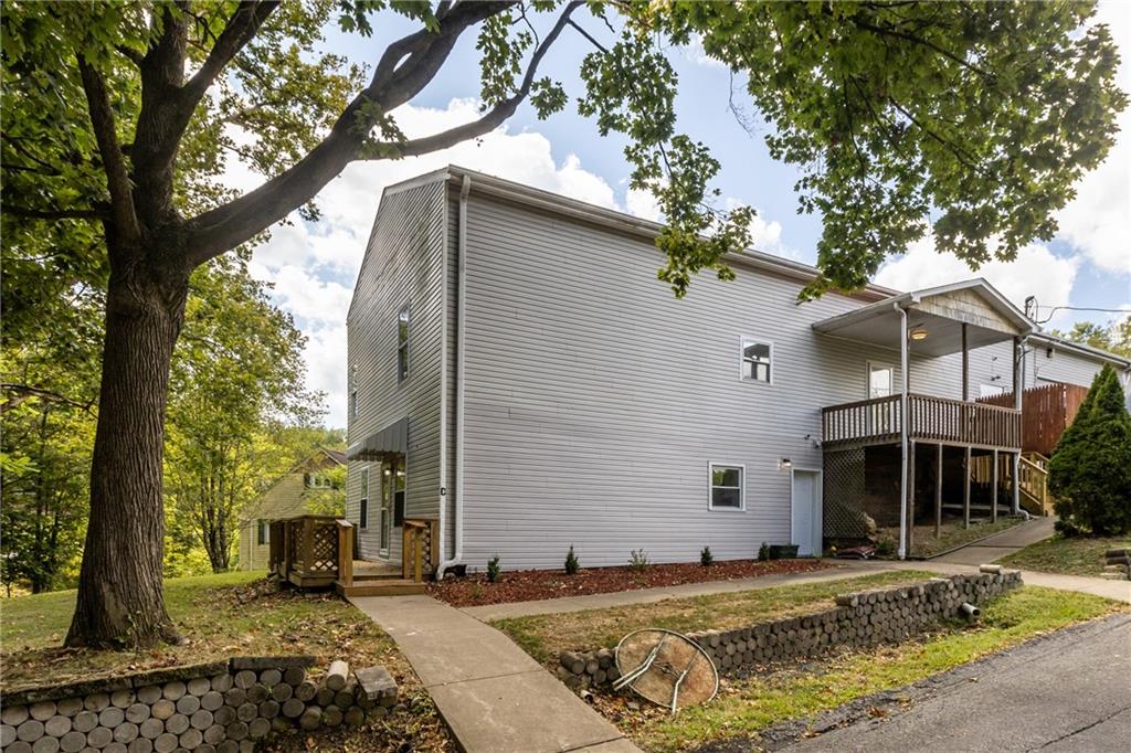 a view of a white house with a small yard and large tree