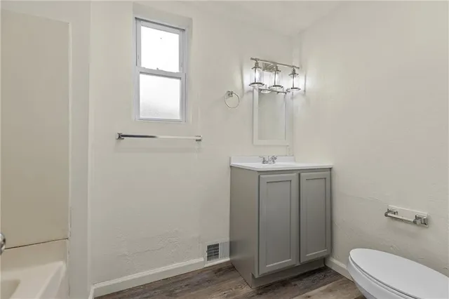 a bathroom with a toilet a sink a mirror and a window