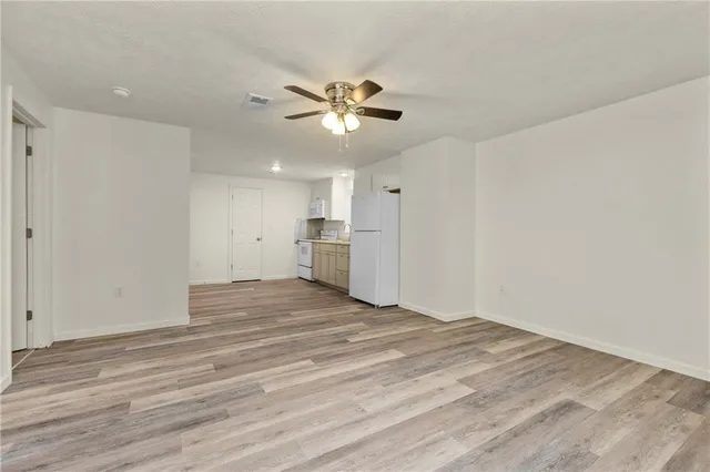 a view of empty room with wooden floor and fan