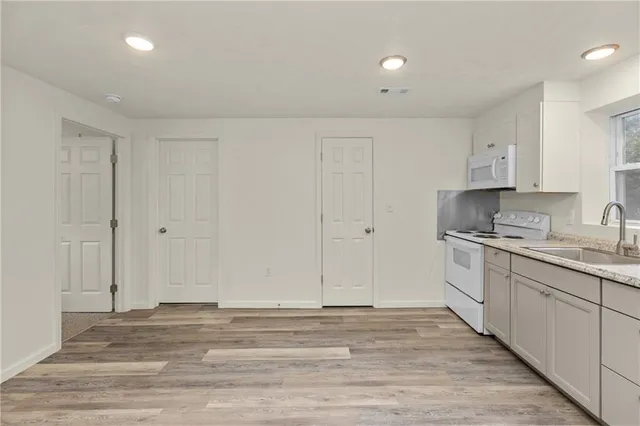 a view of kitchen with granite countertop cabinets and white appliances