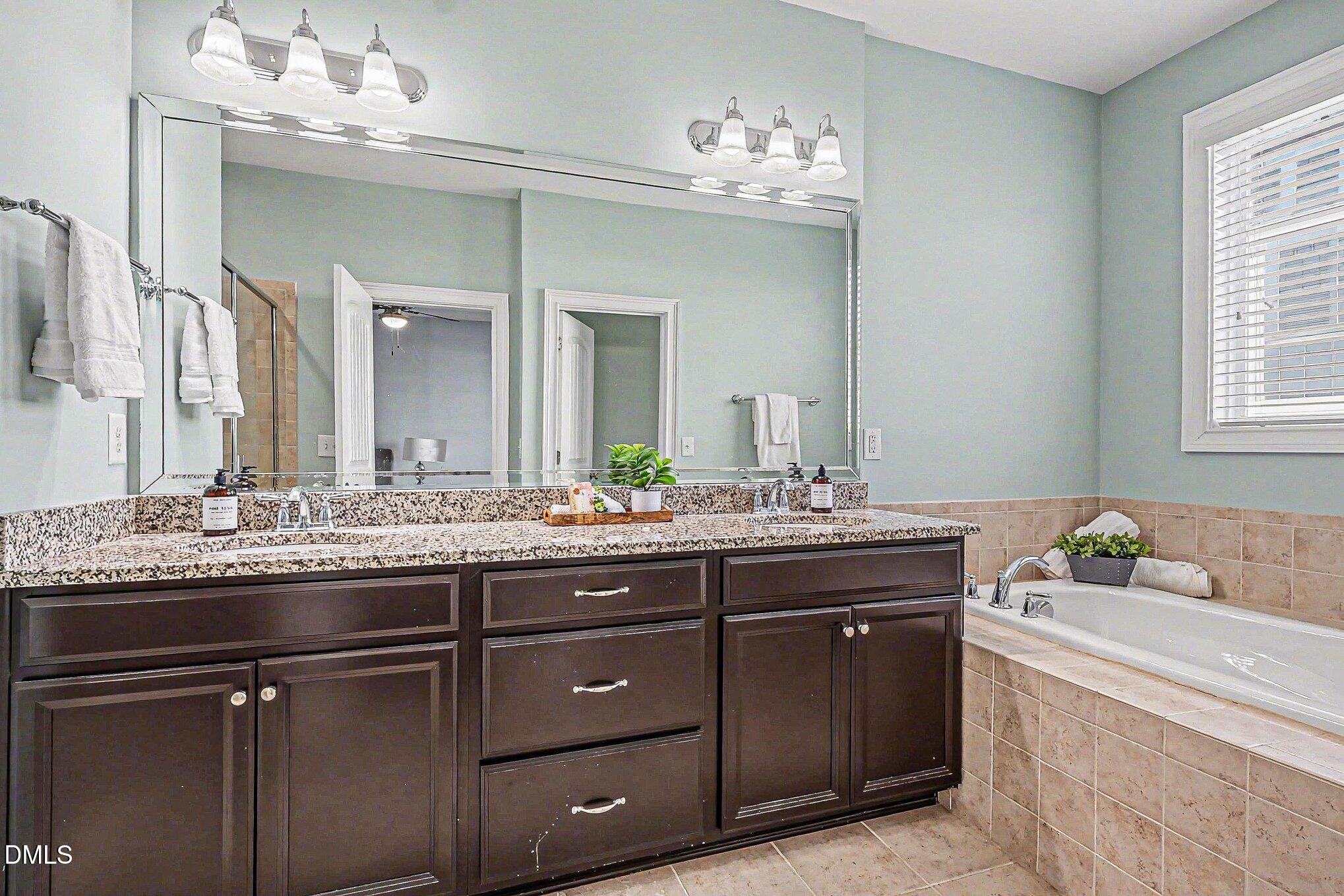 653 Fallon Grove Way Raleigh, NC 27608 - Photo 22 of 38 a bathroom with a granite countertop sink a large mirror and a
