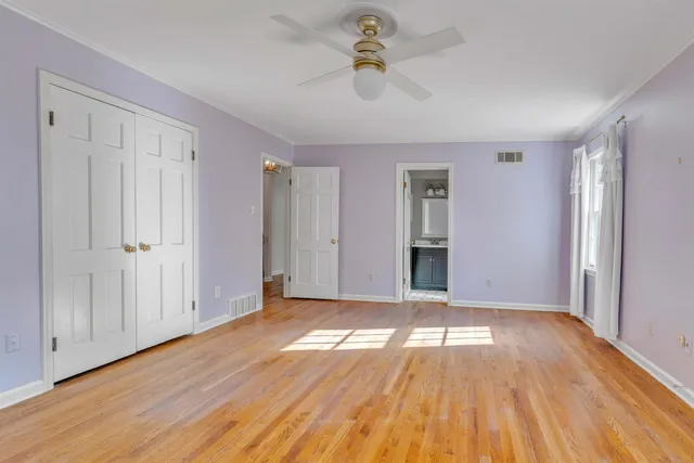 a view of empty room with wooden floor and fan