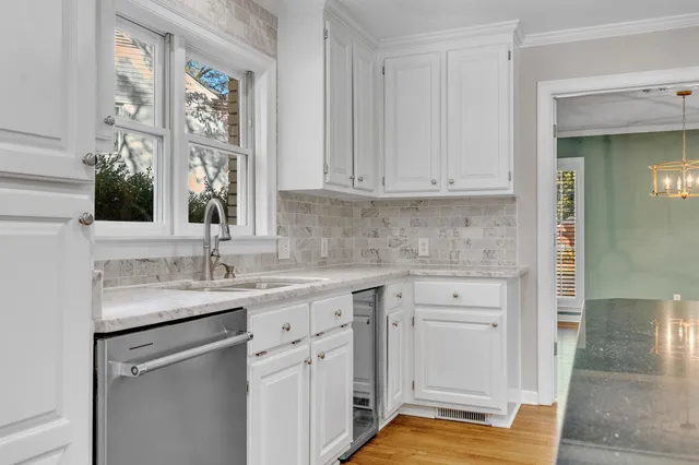 a kitchen with white cabinets and a window