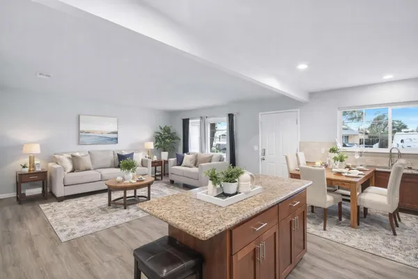 a living room with furniture kitchen view and a large window