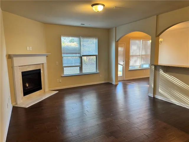 an empty room with wooden floor fireplace and windows