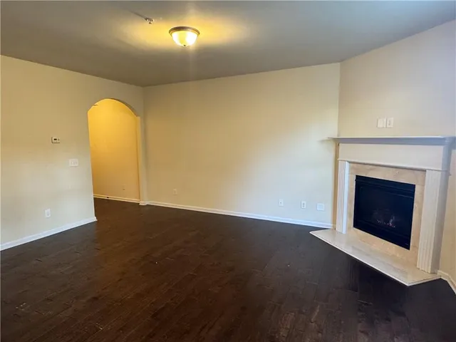 a view of an empty room with wooden floor and a fireplace