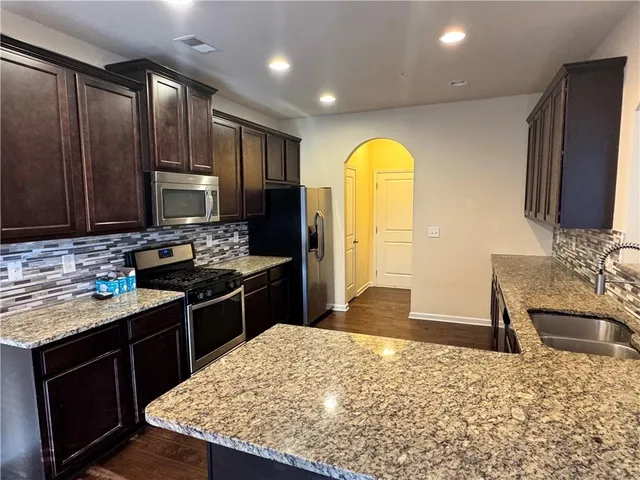 a kitchen with stainless steel appliances granite countertop a sink stove and refrigerator
