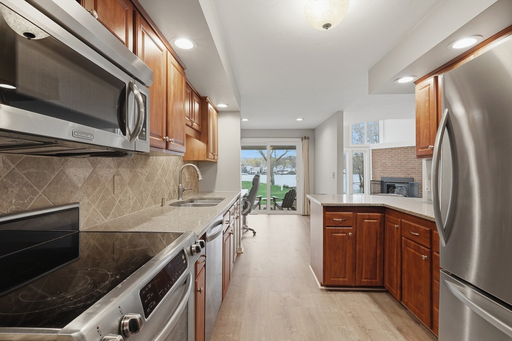 68 South Quinsigamond Avenue, Unit 4 Shrewsbury, MA 01545 - Photo 12 of 37 a kitchen with stainless steel appliances granite countertop a refrigerator a sink dishwasher a stove and a microwave oven with wooden floor